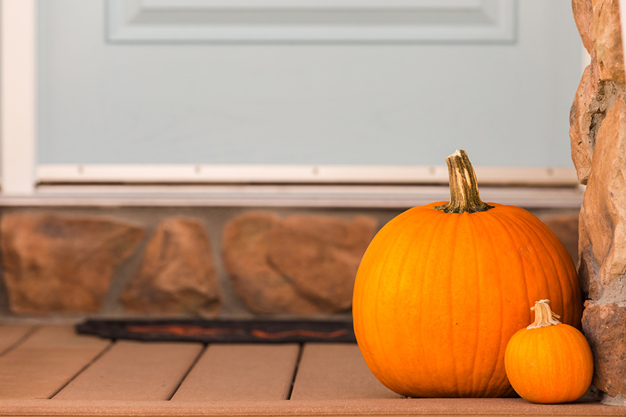 Two pumpkins on a front porch.