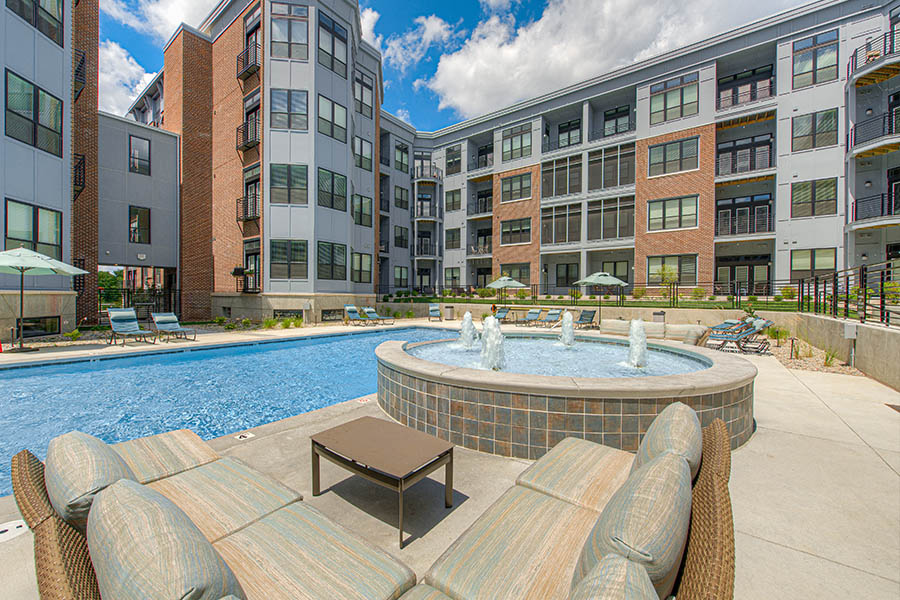 Visiting luxury amenities like this beautiful pool area at Midtown Flats in Carmel is even more enjoyable with a roommate. Pool area with hot tub and outdoor seating