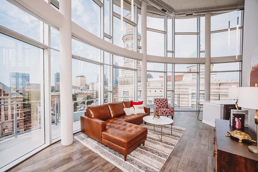 A living room in a high-rise apartment with a wall of windows and a city view.