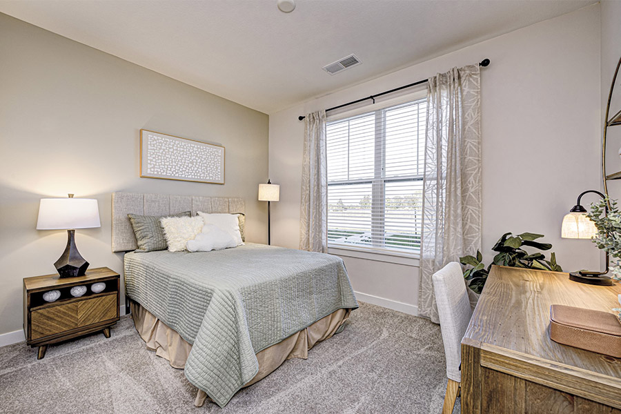 Lamps and the right window treatments help illuminate spaces like this bedroom at Wheelhouse Apartments on the Monon. Apartment bedroom with window and lamps